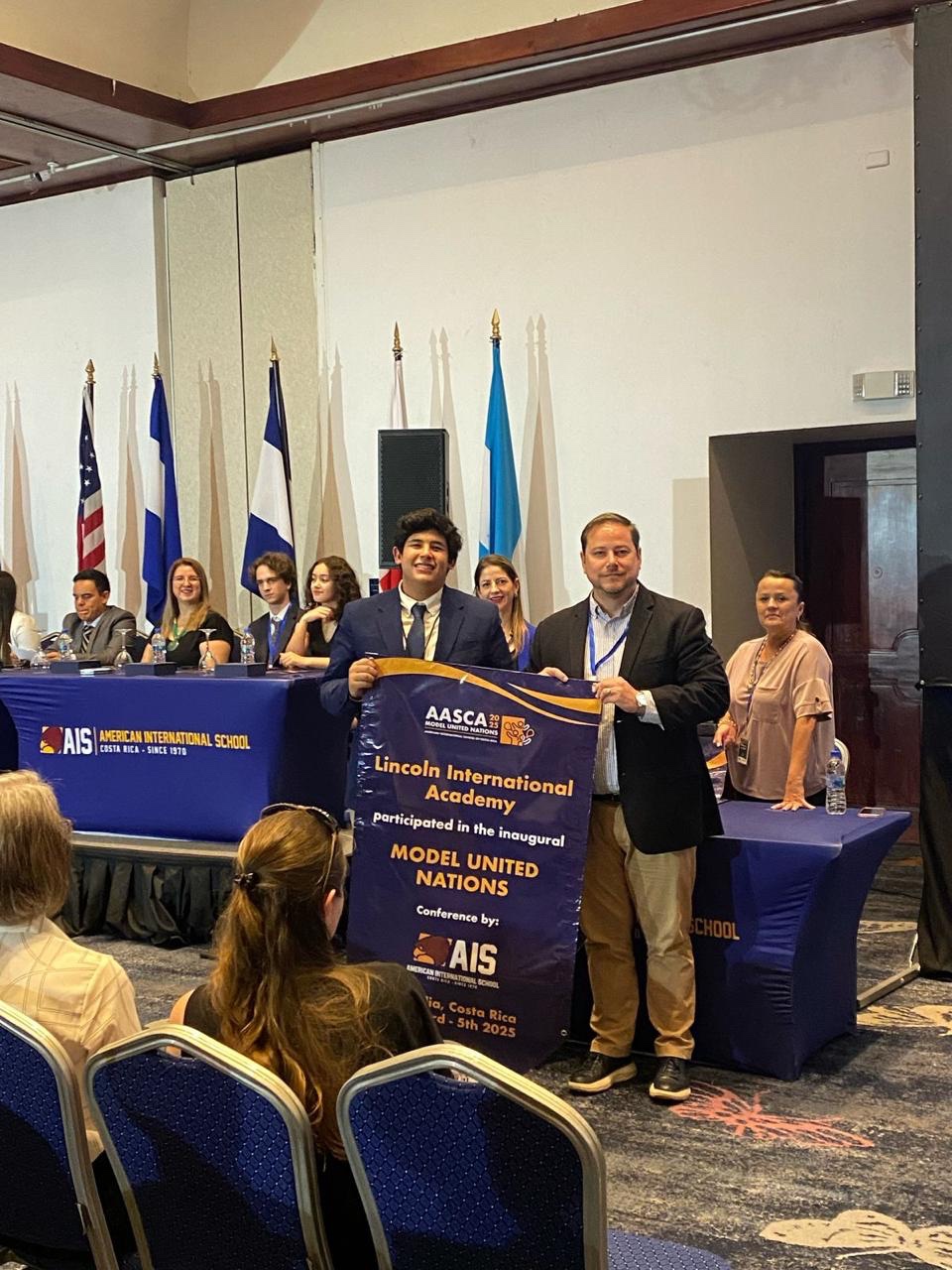 Juan at AASCA Model United Nations holding the Lincoln International Academy participation banner