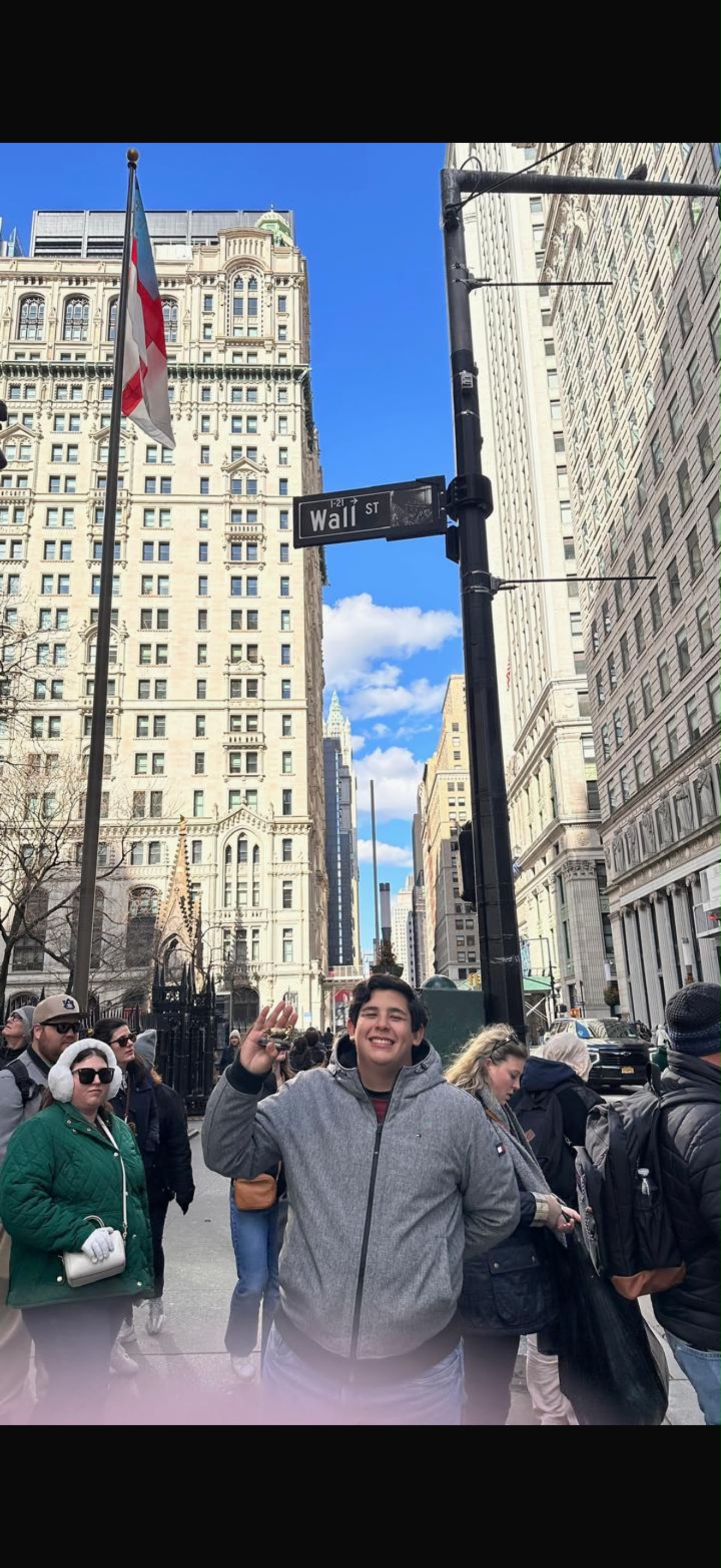 Juan standing beneath a Wall Street sign in New York City